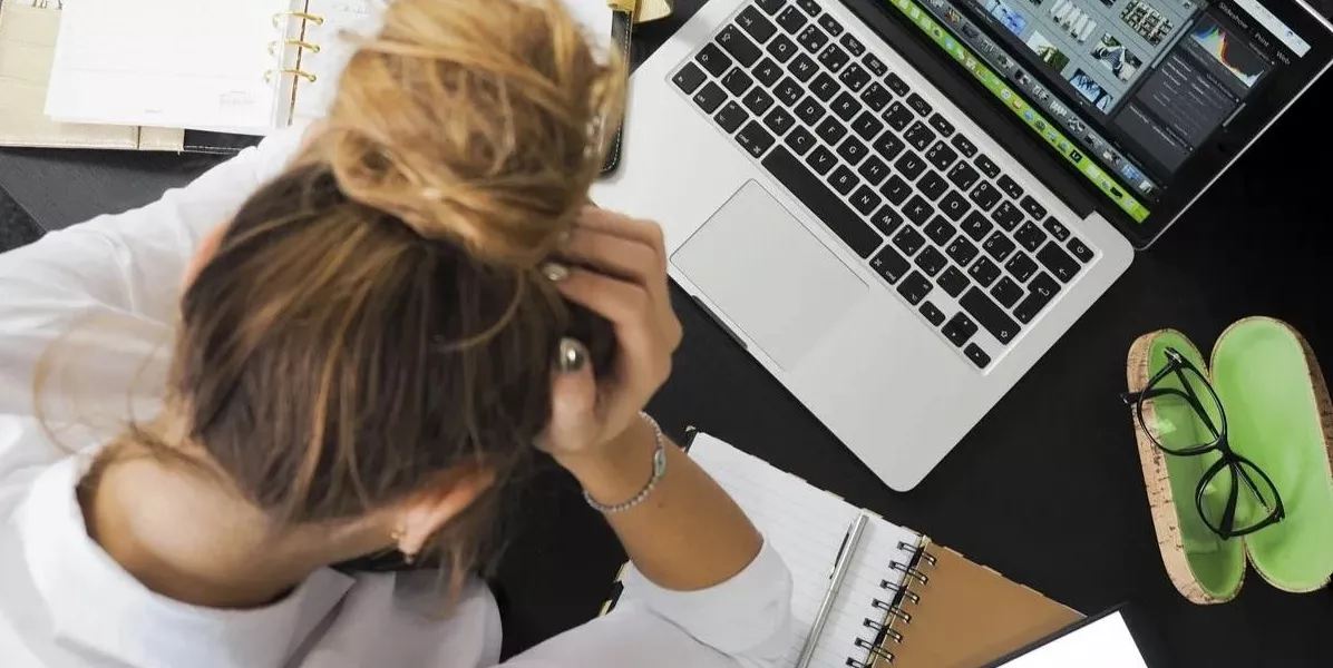 Frustreret, opgivende person der tager sig til hovedet foran sin arbejds computer